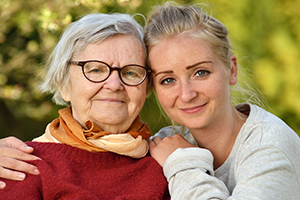 Mother and daughter embracing shoulders and smiling outside